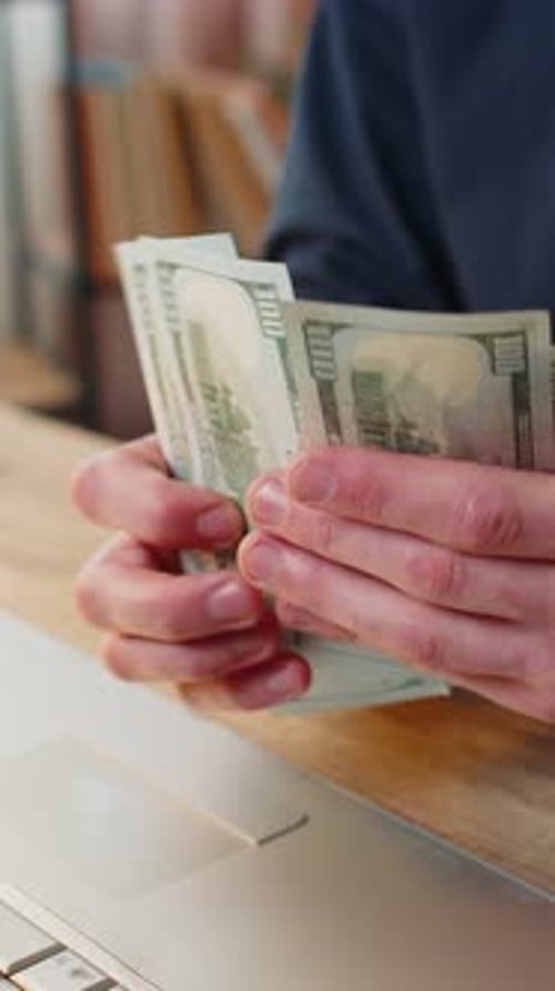 Counting Money at Desk with Laptop Computer