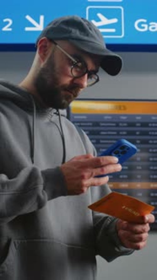 Airport Terminal Man with Backpack Checks Flight Information Scanning Ticket Using Phone