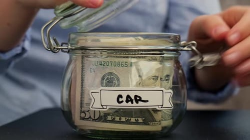 Female Hands Take Money From Glass Jar Full of American Currency Dollars Cash Banknote with Text CAR