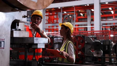 Two heavy industrial engineers check together in a steel factory.