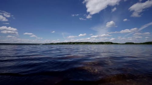 The Water in the Foreground Shimmers From the Sun's Rays and in the Distance the Forest Stretches