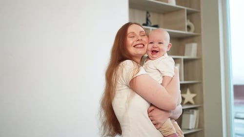 Loving Mother Holds Smiling Baby Indoors