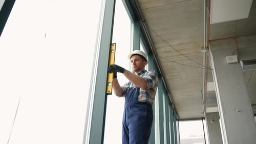 Construction Worker Checking Vertical Alignment of Window Frame