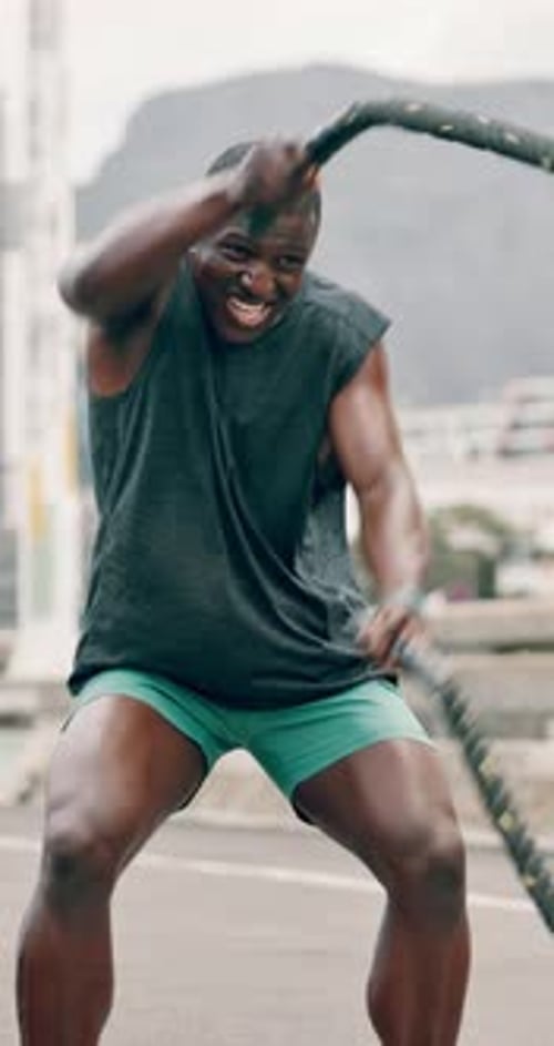 Man, battle ropes and exercise in city for fitness with music, earphones