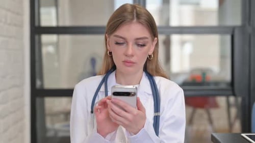 Young Adult Doctor Uses Cellphone in Office
