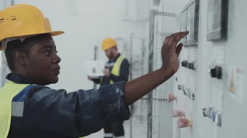 Female Factory Worker Adjusting Settings Of Machine