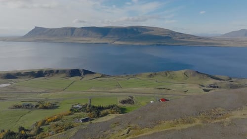 Amazing Hvalfjordur aerial perspective, small hut wrapped in sunny Iceland - drone shot