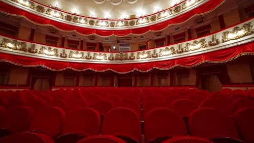 Interior of classical theater. Empty hall with red comfortable seats without audience.
