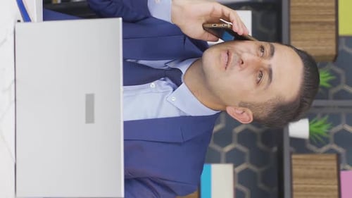 Man in Suit talking on phone by laptop