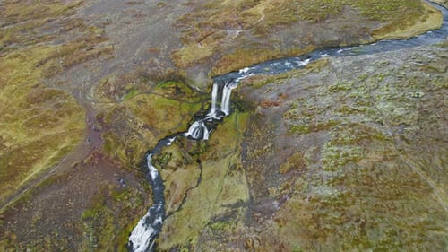 Aerial Drone View Of River Flowing into Icelandic Waterfall Surrounded By Green Yellow Mossy River L