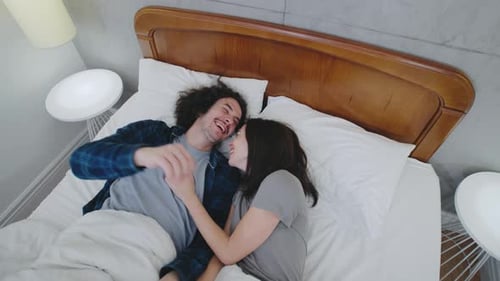 A Romantic Couple Falls Gently Onto a Bed and Embraces Their Warm Hug and Smiles Reflect Deep