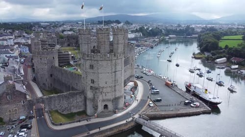 Ancient Caernarfon castle Welsh harbour town aerial view medieval waterfront landmark right orbit to