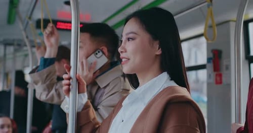 Close View of Asian Girl Standing in Middle of Moving Train or Bus Woman Turning Head to Look