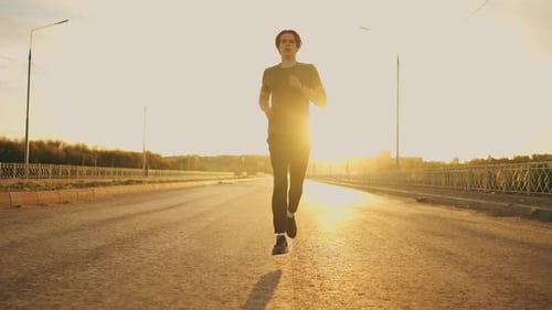 Young Sporty Man is Training Alone in Morning Running on Road in Sunny Weather Workout for Keeping
