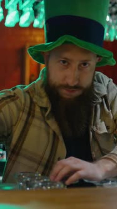 Portrait of Bearded Barman in Leprechaun Hat Serving Pint of Green Beer