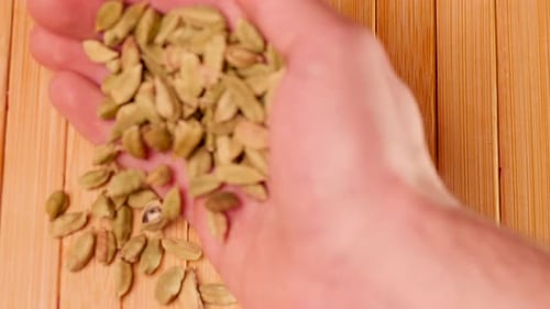 green cardamom pods being poured from hand
