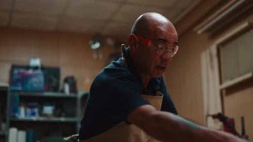 Man Puts on Safety Gear in Workshop