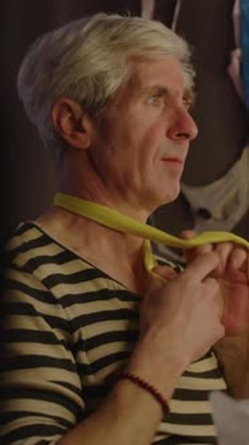 Adult Man Tying Yellow Scarf Around Neck Indoors