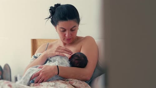 Woman Nursing Her Infant in Bed at Home