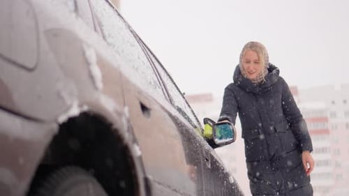Woman Clears Snow off Car in Winter Urban Scene