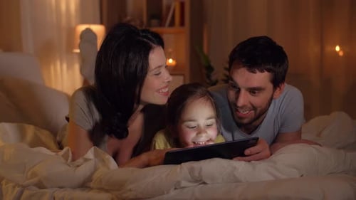 Loving Family Using Tablet Together in Bed at Night