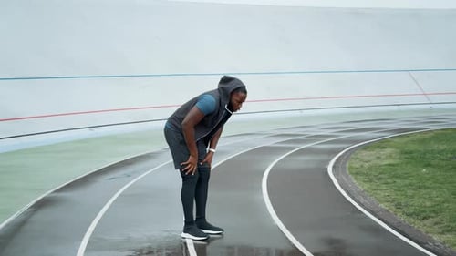 Active Afro Runner Jumping on Place at Stadium. Male Jogger Warming Before