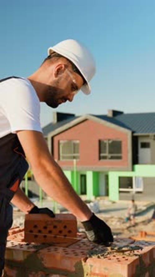 Builder Laying Bricks on Construction Site
