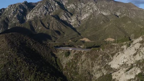 Beautiful aerial fly over road in the green mountains during golden hour