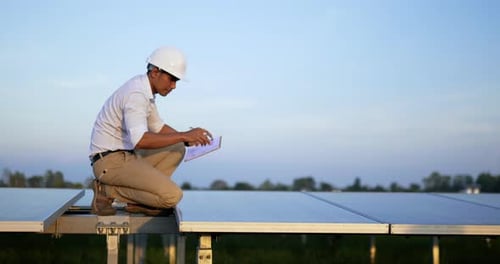 Asian Young Inspector Engineer man checking solar panel operation in solar station