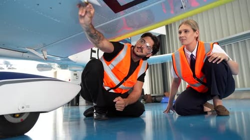 Male and Female Aircraft Technicians Inspecting a Small Plane in Hangar