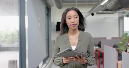African american businesswoman using digital tablet while walking in office