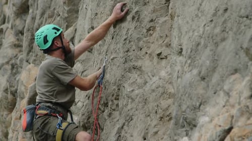 Man Climbing Up Rock and Putting Chalk on Hand