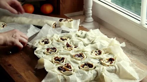 Baker Slicing Sweet Pastry Roll into Small Pieces in Sunlit Kitchen