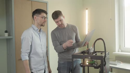 3D printer. Two male engineers employees discussing project watching 3d printer machine modeling