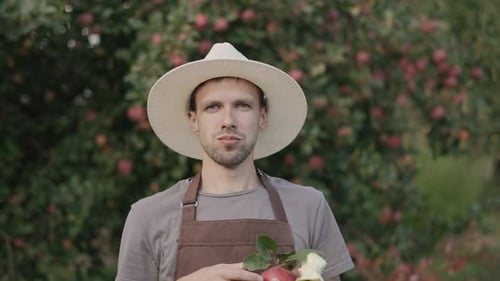 Portrait of Gardener Chewing Apple in Garden Near Fruit Tree