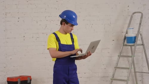 Young Man With Laptop in Repairman Uniform