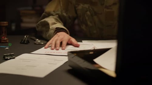 Soldier Reads Classified Documents with Magnifying Glass