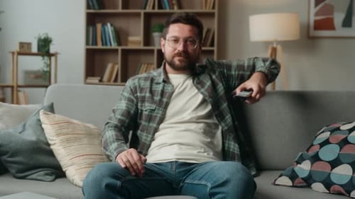 Man Relaxes on Sofa and Watches Television