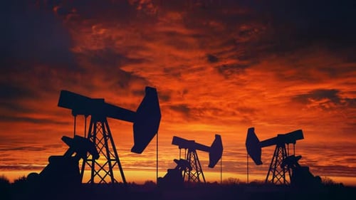 Oil Pumpjacks Silhouetted Against Fiery Sunset Sky
