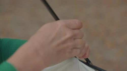 Person Fastening Tent Clip Onto Pole with Greensleeved Hands Outdoors Detailed Image of Hands