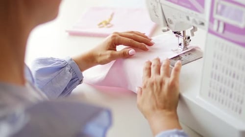 Woman clothing designer sews fabrics on a sewing machine. Needlework