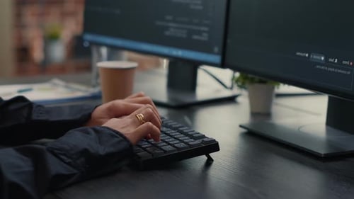 Entwickler geben den Code auf der Bürotastatur mit sitzender Arbeitsstation ein