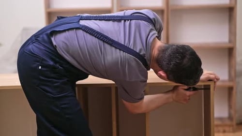 Furniture Assembly Worker Tightening Screws in Wooden Rack Delivered to Apartment
