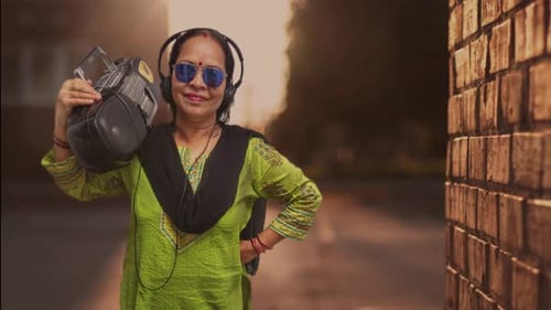 Une jolie dame élégante à la mode tenant un système de musique rétro, un juke-box et debout dans une allée