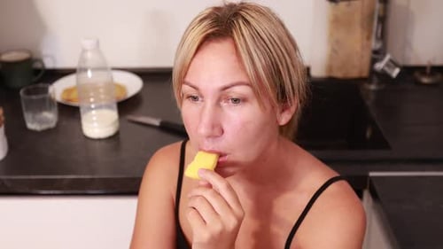 Woman Eating Fruit in the Kitchen