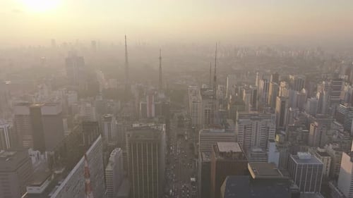 Vasta paisagem urbana de São Paulo ao pôr do sol na Avenida Paulista com atmosfera de neblina