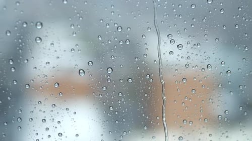 blurry city background on a stormy raining day. rain drops on window