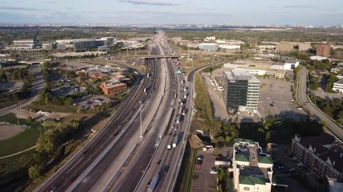 Drone push in shot of a busy highway 3 lanes 1 way. View at cars joining the traffic. Golden hour. S