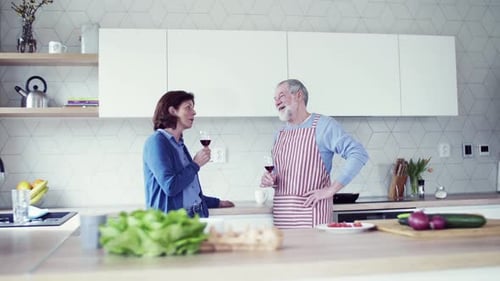Mature couple drinking wine together in modern kitchen