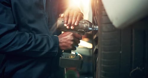 Mechanic Using Power Tool to Fix Car Tire